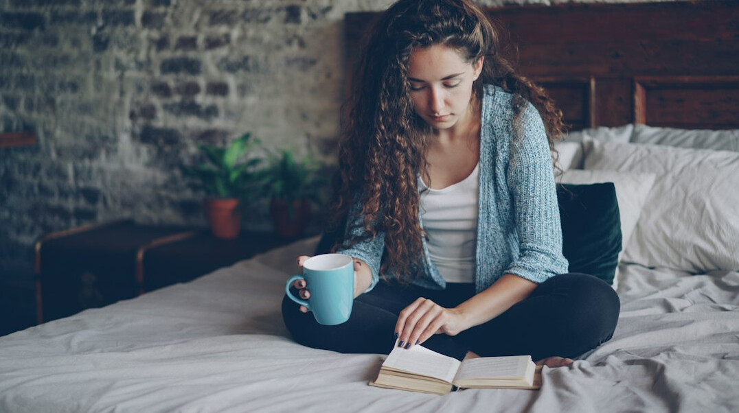 Brazilian woman writing reflectively in a journal at home by the window